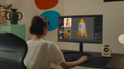 A woman in glasses is focusing on a computer screen as she edits images with a wirelessly connected mouse and keyboard