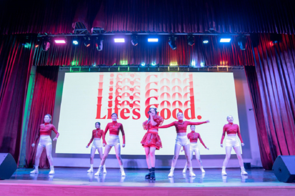 A picture of people performing on stage with the Life's Good logo behind