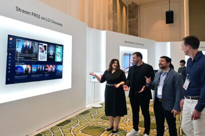 A group of attendees are exploring webOS content on a wall-mounted LG smart TV at webOS Summit 2024
