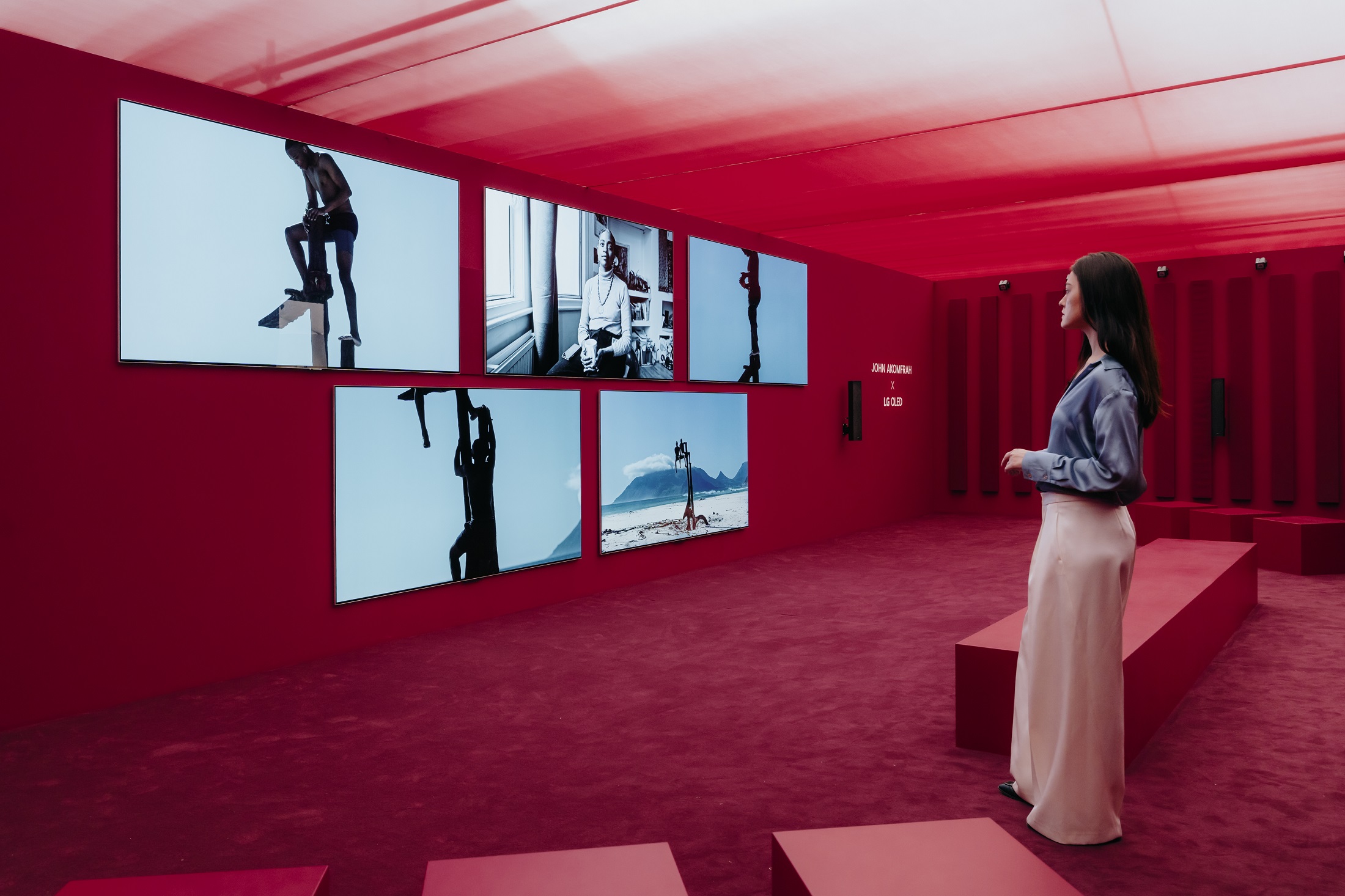 A woman observes the artwork by John Akomfrah, displayed on LG OLED TVs
