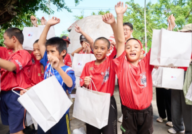 A picture of a group of children from the school holding gift bags from LG
