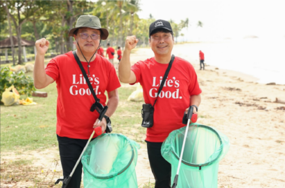 A picture of LG Singapore employees posing for a picture with their fists up at the ocean