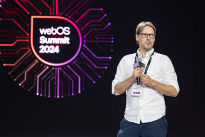 Jukka Saarelainen, the first-place winner of the LG webOS Hackathon 2024, holds a microphone on stage while giving a speech