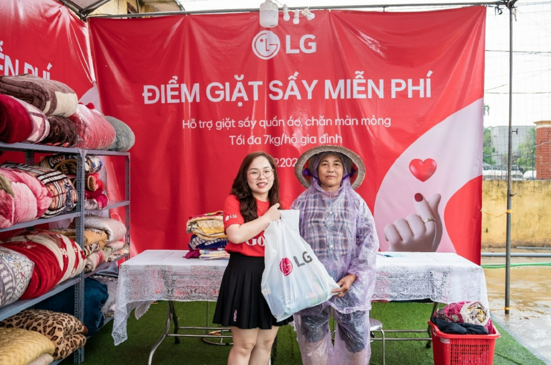 A photo of an LG employee delivering plastic bags with blankets with the LG logo to a Vietnamese citizen