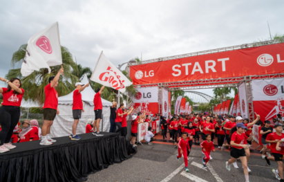 A photo of people running hard at the start line of the LG Marathon in Malaysia, with people waving Life's good flags on the sidelines