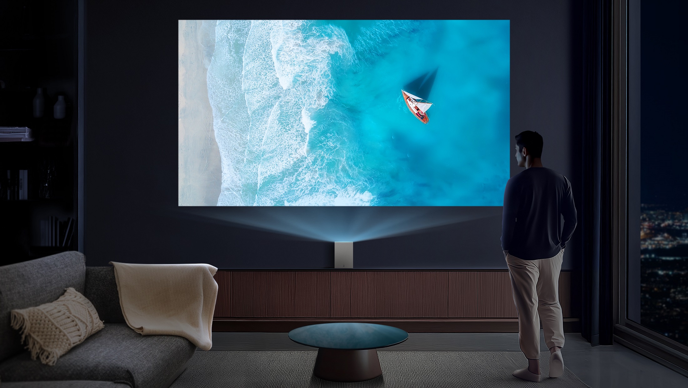 A man watching a high-resolution ocean scene projected onto a large screen by LG CineBeam S